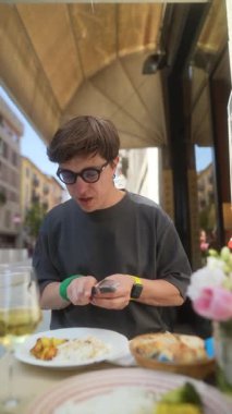 Genç bir insan güneşli bir kafede yemek yerken rahat bir yemek anı yakalıyor.