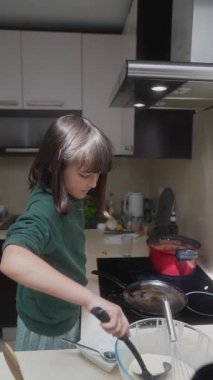 Genç bir çocuk, parlak ve renkli bir mutfakta yemek pişirme, harika mutfak becerileri sergiliyor.