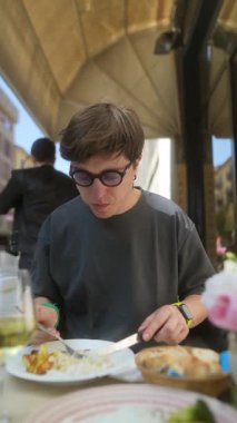 Lezzetli yemeklerle dolu canlı bir kafede yemeğin tadını çıkaran genç bir adam.