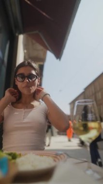 Güzel bir kafede nefis yemeğinin tadını çıkaran nefis yemekler ve ferahlatıcı şaraplar sunan bir kadın.