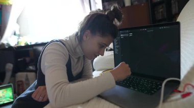 Konforlu bir ortamda dizüstü bilgisayarı üzerinde çalışan odaklanmış genç bir kadın kendini adamışlık ve yaratıcılık sergiliyor..