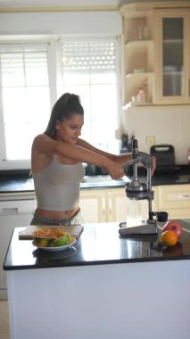 Şık bir mutfakta, bir kadın taze meyve sıkmak için pres kullanıyor, sağlıklı ve hayat dolu bir hayat sürüyor.