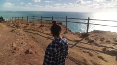 Bir insan muhteşem bir okyanus manzarasına tepeden bakar. Huzuru ve güzelliği yakalar..