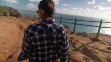 Huzurlu bir ortamda nefes kesici okyanus manzarası seyreden, nefes kesici bir kıyı şeridi boyunca rahatça yürüyen bir insan.