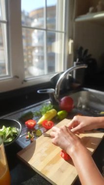 Yetenekli bir şef, güneşli bir mutfak alanında çeşitli taze sebzeleri ustalıkla dilimliyor.