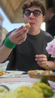 Genç bir adam arkadaşlarıyla açık hava yemeğinden zevk alır. Birlikte içtikleri yemek ve içeceklerin tadını çıkarır.