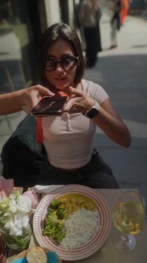 Şık bir genç kadın, canlı bir kafede otururken yemeğin tadını çıkarıyor.