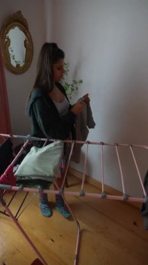 Rahat ve rahat bir ortamda, genç bir kadın çamaşırlarını kurutma askısı kullanarak ustalıkla idare ediyor.