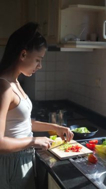 Yetenekli bir kadın aydınlık bir mutfakta taze, renkli sebzeler hazırlar ve sağlıklı yemekler pişirir.