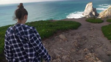 Kaygısız genç bir kadın, çarpıcı okyanus manzarası ve canlandırıcı temiz havanın tadını çıkararak kıyı şeridini keşfediyor.