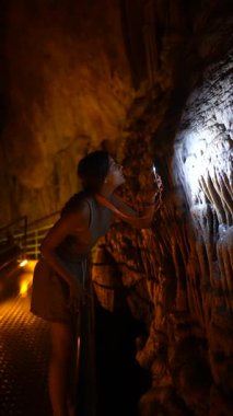 Bir insan el feneriyle aydınlatılan mağara duvarlarını inceliyor ve şaşırtıcı doğal oluşumları ortaya çıkarıyor.