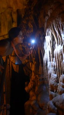 Bir insan loş bir mağaradaki karmaşık mağara yapılarını araştırır, güzelliği ön plana çıkarır..