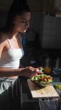 Parlak ve davetkar bir mutfak ortamında genç bir kadın ustalıkla ve ustalıkla lezzetli taze bir salata hazırlar.
