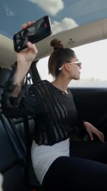 Şık bir kadın arabasında tutkuyla şarkı söylüyor, şehirde geziyor ve canlı enerjisini sergiliyor.