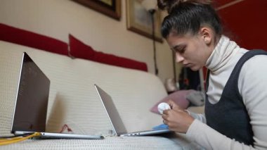 İki ayrı dizüstü bilgisayarda ustalıkla odaklanmış bir birey, modern uzaktan çalışma dinamikleri sergiliyor.