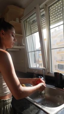 Parlak bir mutfakta kedisiyle neşeyle etkileşime giren bir kadın, mutlu bir ev hayatının özünü yakalıyor.