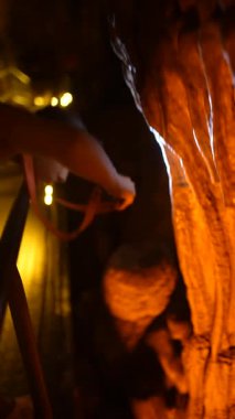 Meraklı bir ziyaretçi, el feneriyle güzelce aydınlatılan büyüleyici mağara yapılarını inceliyor.