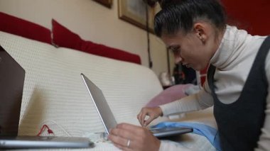 Konforlu bir ev ortamında, bir kadın dizüstü bilgisayar görevleriyle yakından ilgilenir, modern uzaktan kumandalı çalışmalara örnek olur.