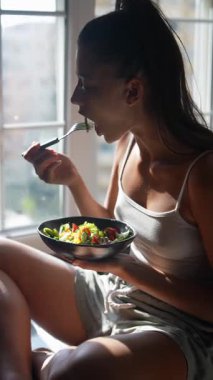 Bir insan, sağlıklı yaşam ve refahı yansıtan, sıcak ve doğal ışıkta renkli bir salatadan hoşlanır.