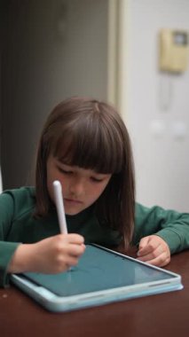 Yaratıcı bir çocuk etkileyici dijital sanat veya notlar üretmek için bir tablet ve stil kullanır.