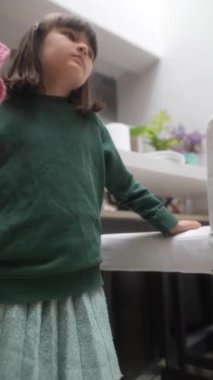 Büyüleyici yeşil bir süveter giymiş genç bir çocuk, canlı çevrelerini keşfederken düşünceli bir şekilde bakıyor.