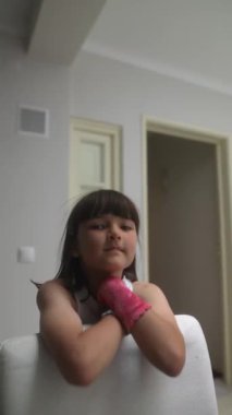 Genç bir kız neşeli ve yaratıcı bir şekilde renkli kol kollarıyla neşeli, parlak bir iç mekan ortamında poz veriyor.