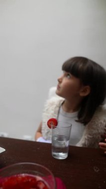 Renkli ve canlı kol aksesuarları takan genç bir çocuk büyüleyici bir masada hoş bir içkinin tadını çıkarıyor.,