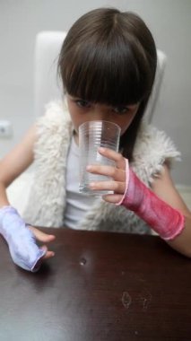Elleri bandajlı, mutlu bir şekilde içkisini yudumlayan, direnç ve kararlılığını gösteren genç bir kız.