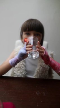 Bir çocuk taze çilekle süslenmiş bir bardak suya odaklanır. Yaratıcılık ve neşe sergiler.