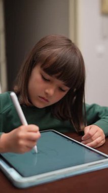 Bir çocuk tablet ve stil kullanarak dijital olarak çizmeye odaklanmış, yaratıcılık ve teknoloji sergiliyor.