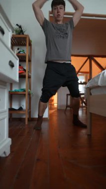 Günlük giysiler giymiş bir insan evin içinde şakacı bir şekilde hareket ediyor, sıcak ve samimi bir atmosfer sergiliyor.