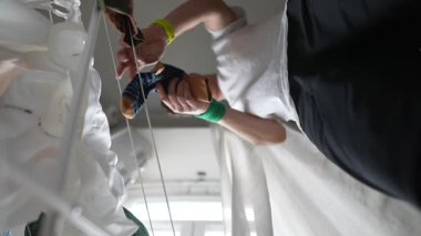 İyi aydınlatılmış bir iç mekanda düzgün bir giyim markasının yanında dururken çeşitli ayakkabıları ustalıkla idare eden bir insan.