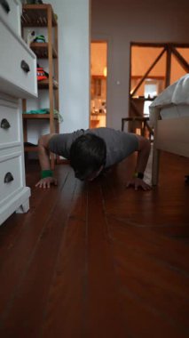 Konforlu bir ev ortamında, bir insan enerjik bir şekilde şınav çekiyor, fitness ve sağlığın önemini vurguluyor.