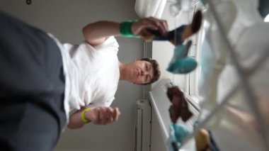 Genç bir adam çeşitli nesnelerle benzersiz bir düşük perspektiften temas kurar, kapalı alanda geçen anları etkili bir şekilde yakalar.