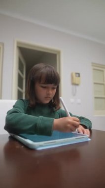 Genç bir çocuk, rahat bir ortamda yaratıcılığı ve dijital öğrenmeyi gösteren bir tablet kullanır..