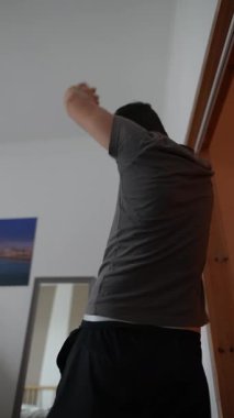 Bir birey kollarını kaldırarak esneme egzersizleri yapıyor ve ev egzersizlerini etkili bir şekilde gösteriyor.
