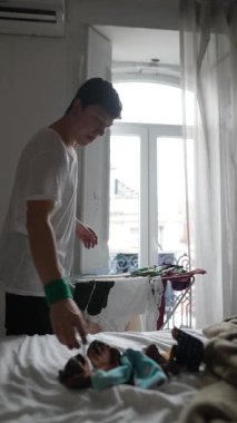 Kendini adamış bir bakıcı, sıcak doğal ışıkla dolu parlak, havadar bir odada neşeli bir bebeğe sevgiyle bakar.
