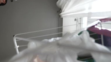 Bir insan, ev idaresinde yaratıcılığını göstermek için iç mekanda giysileri ustalıkla düzenler ve idare eder..