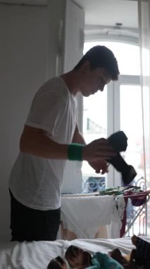 Genç bir adam, parlak, sıradan ve davetkar bir şekilde çamaşırları katlarken ve düzenlerken dikkatle gözlemlenir.