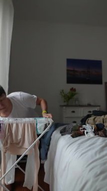Genç bir insan, günlük yaşamda rutini vurgulamak için yumuşak bir odada temiz giysileri katlar.