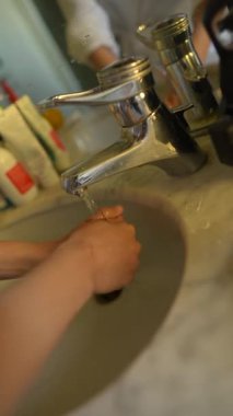 Suyun altında yıkanan ellerin yakınlığı, hijyen ve sağlığın önemini vurguluyor.