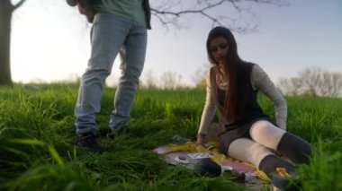 İki yakın arkadaş gün batımında canlı yeşil bir tarlada rahat bir battaniyede keyifli bir oyun oynuyorlar.