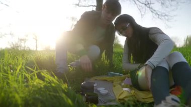 Sıcak güneş ışığı altında yemyeşil bir alanda huzurlu ve huzurlu bir piknik anı yaşayan bir çift.