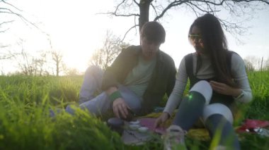 Bir çift güzel bir parkta pikniğin tadını çıkarıyor, atıştırmalıkların ve arkadaşlığın tadını çıkarıyor, hatıralar yaratıyor.