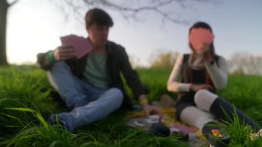 Neşeli bir çift, güneşli bir günde, güzel, yemyeşil bir parkta neşeli bir kart oyununa girişir.