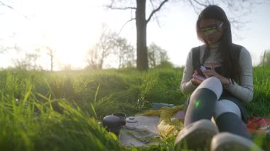 Genç bir kadın aydınlık, güneşli bir tarlada huzur içinde oturuyor, doğanın ortasında huzurlu bir anın tadını çıkarıyor.