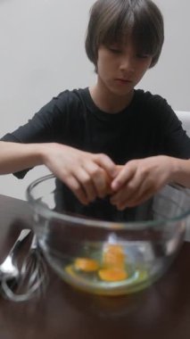 Genç bir çocuk, taze yumurtaları karıştırma kabına ustalıkla yerleştiriyor. Yetiştirme becerilerini ustalıkla sergiliyor.