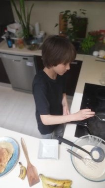 Şık ve modern bir mutfakta, genç bir çocuk zevkle yemek pişiriyor, lezzetli bir gözleme kahvaltısı hazırlıyor.
