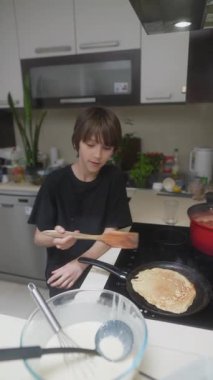 Genç bir çocuk, çağdaş bir mutfakta krep pişirmeyi, yaratıcılığı ve aşçılık becerilerini sergilemeyi sever..