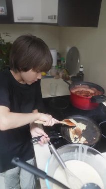 Genç bir çocuk, modern bir mutfakta lezzetli yemekler hazırlarken neşeyle etkileyici yemek yapma becerileri sergiliyor.